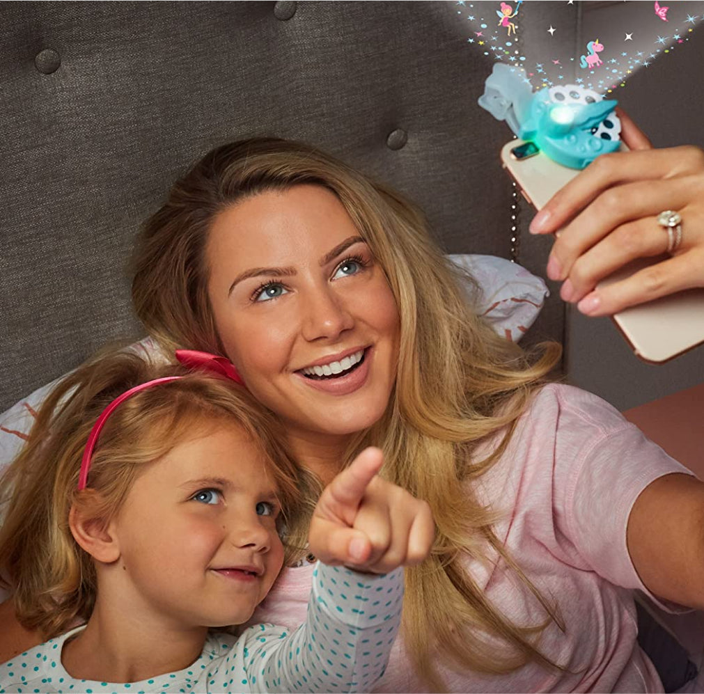Blonde mom smiles as she projects the Moonlight image onto the ceiling. Her daughter points toward it.