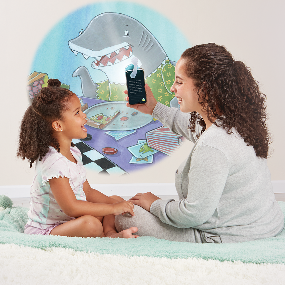 Mother reading to daughter, using the Moonlite projector to project the story images on the wall