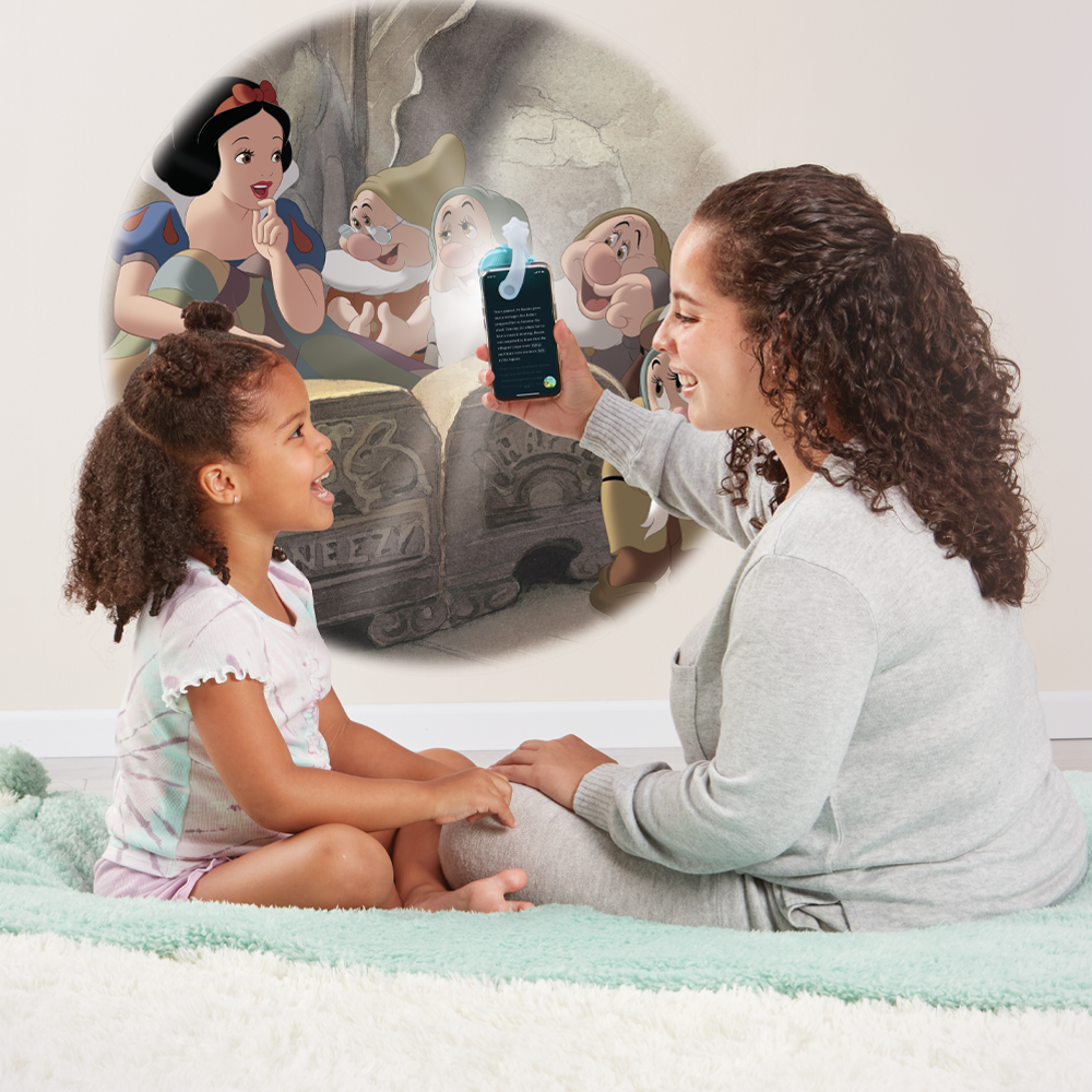 Mother reading to daughter, using the Moonlite projector to project the story images on the wall