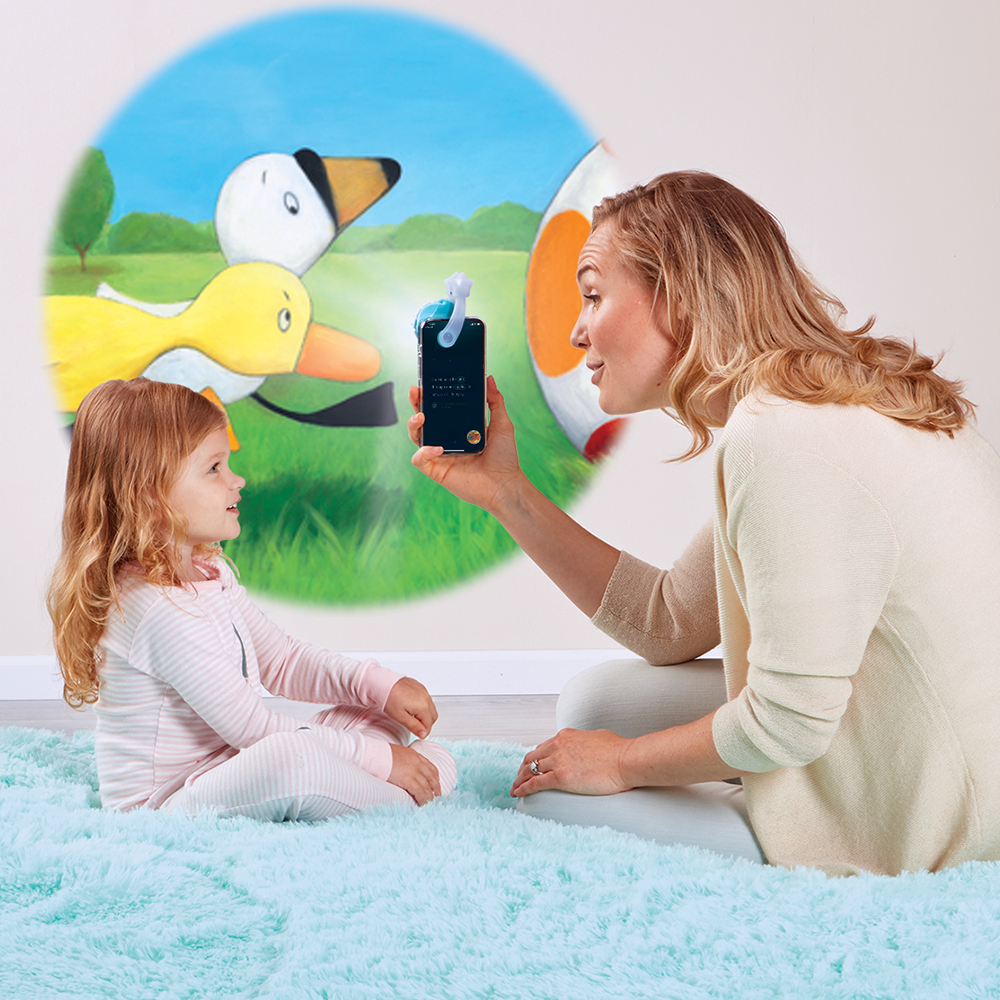 Mother reading to daughter, using the Moonlite projector to project the story images on the wall