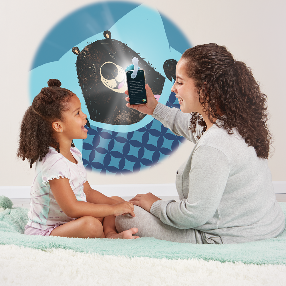 Mother reading to daughter, using the Moonlite projector to project the story images on the wall