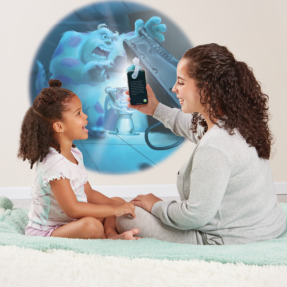 Mother reading Monsters, Inc. to daughter, using the Moonlite projector to project the story images on the wall