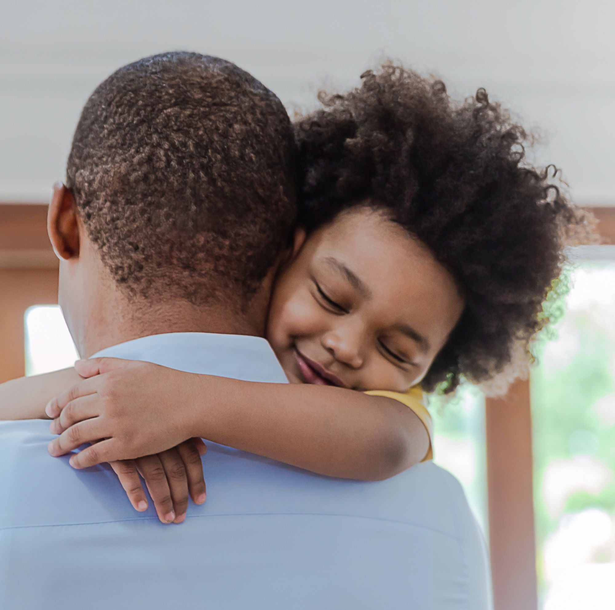 A kid smiling while hugging his dad.