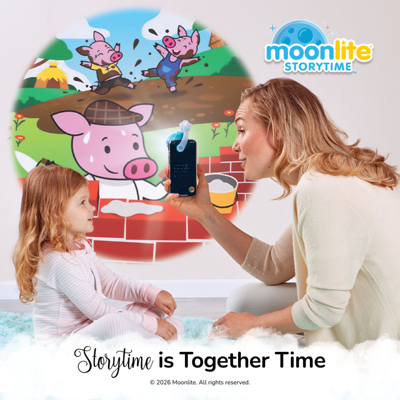 A woman and a young girl sit together indoors, with the woman holding a smartphone that projects a colorful cartoon pig story scene. The Moonlite Storytime brand logo appears in the top right, and the text 'Storytime is Together Time' is shown at the bottom.